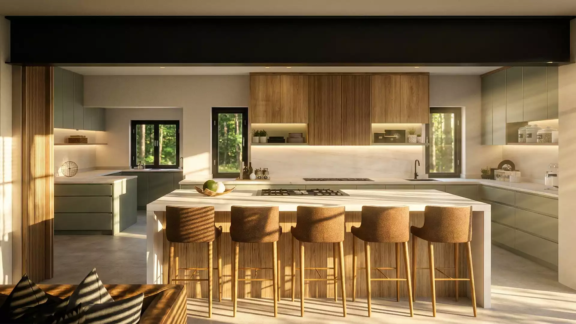 A warm and inviting modern kitchen featuring wood-paneled upper cabinetry, soft green lower cabinets, a large central island with five brown bar stools, and ample natural light streaming through windows overlooking a wooded area.