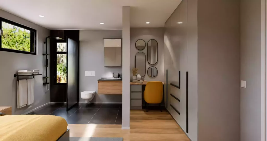 A modern bedroom suite featuring a built-in dressing area with grey wardrobes, a yellow vanity chair, and a partition wall leading into an open en-suite bathroom with grey tiled flooring.