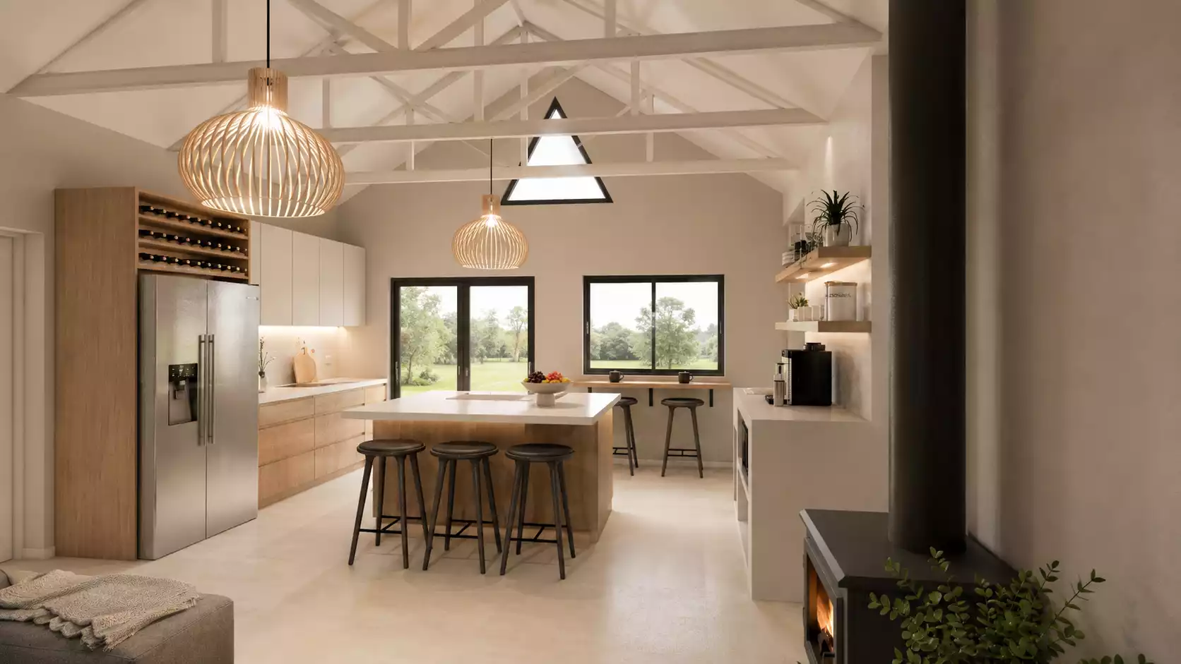 A warm and inviting open-plan farmhouse-style kitchen featuring a high vaulted ceiling with exposed beams, a central island with bar stool seating, natural wood cabinetry, and large pendant lights, all centered around a cozy fireplace and a view of the lush green landscape outside.