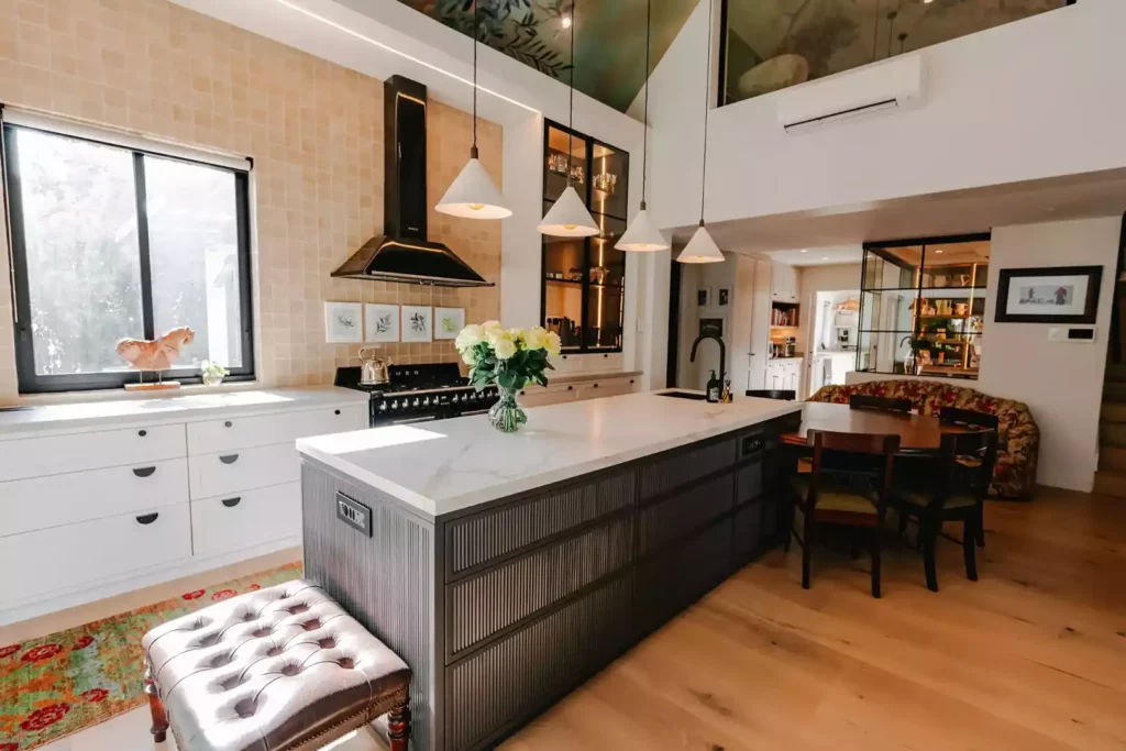 Modern kitchen with a large dark island, white cabinets, and a dining area.