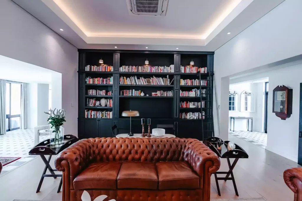 Modern library with black bookshelf and leather sofa.