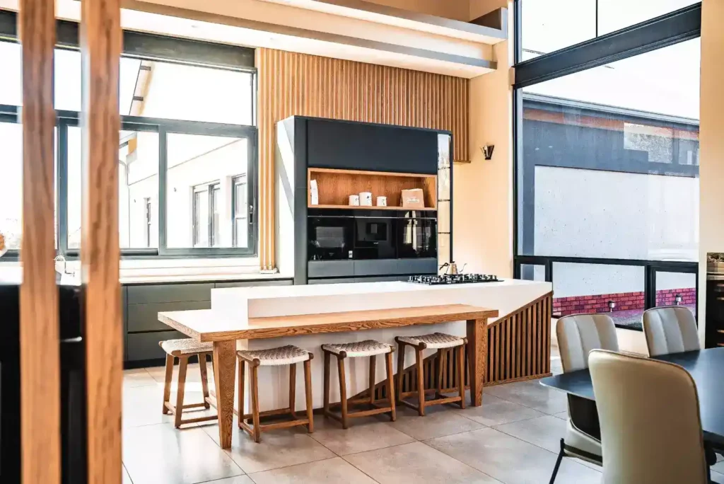 Modern kitchen with a large island featuring a wood-slat base and an integrated wood dining table.