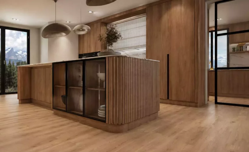 : A modern, luxury kitchen featuring extensive warm wood cabinetry, a large kitchen island with a marble countertop, an integrated glass-fronted display section, and wood-slat detailing. The space is accented by distinctive pendant lights, views of mountainous terrain through large windows, and a doorway with black framing leading to a staircase area.